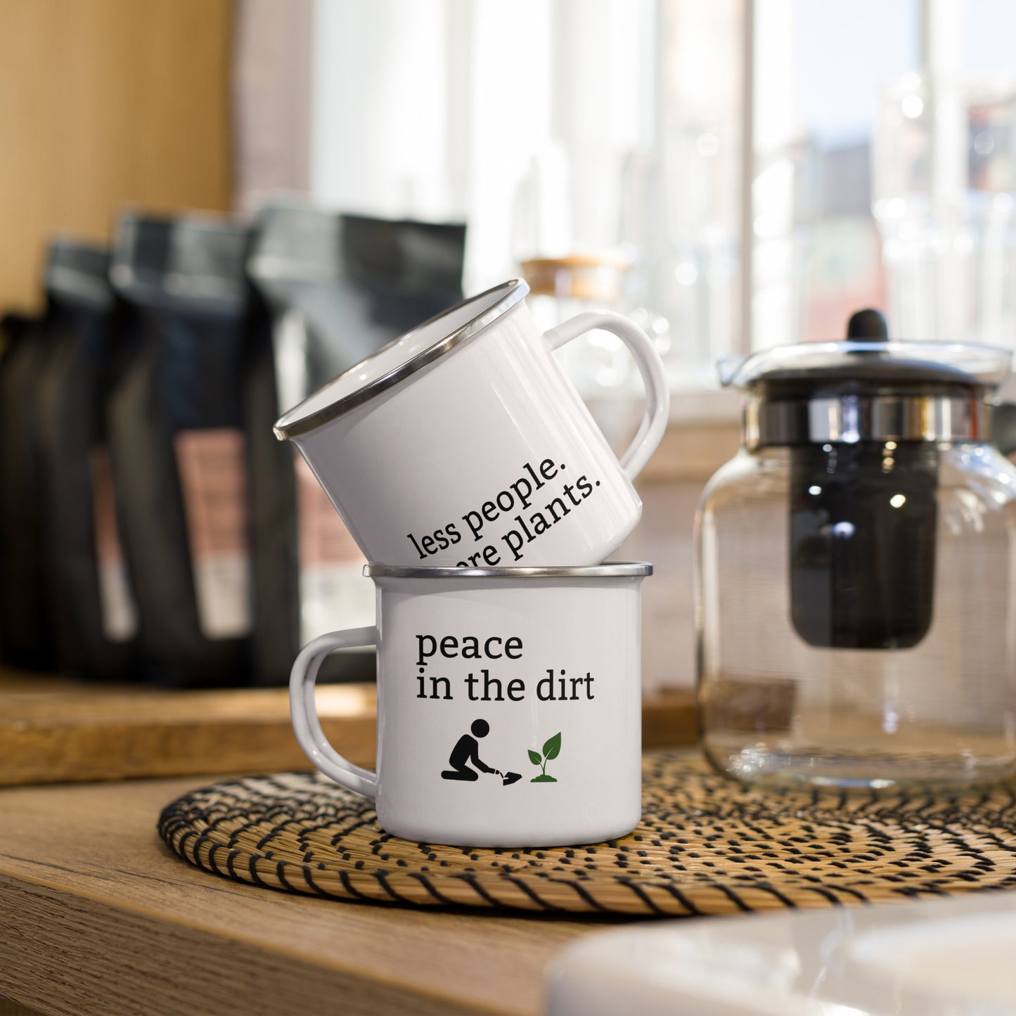White enamel mug with black rim featuring “Peace in the dirt” and “Less people, more plants” text