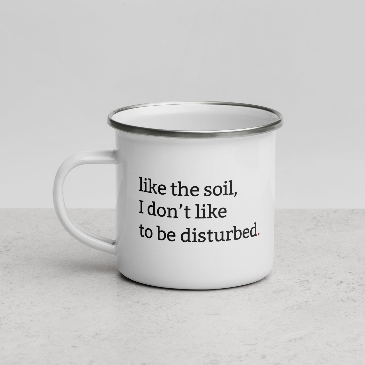 White enamel mug with black rim featuring “Like the soil I don’t like to be disturbed” and “Tolerance is seasonal” text
