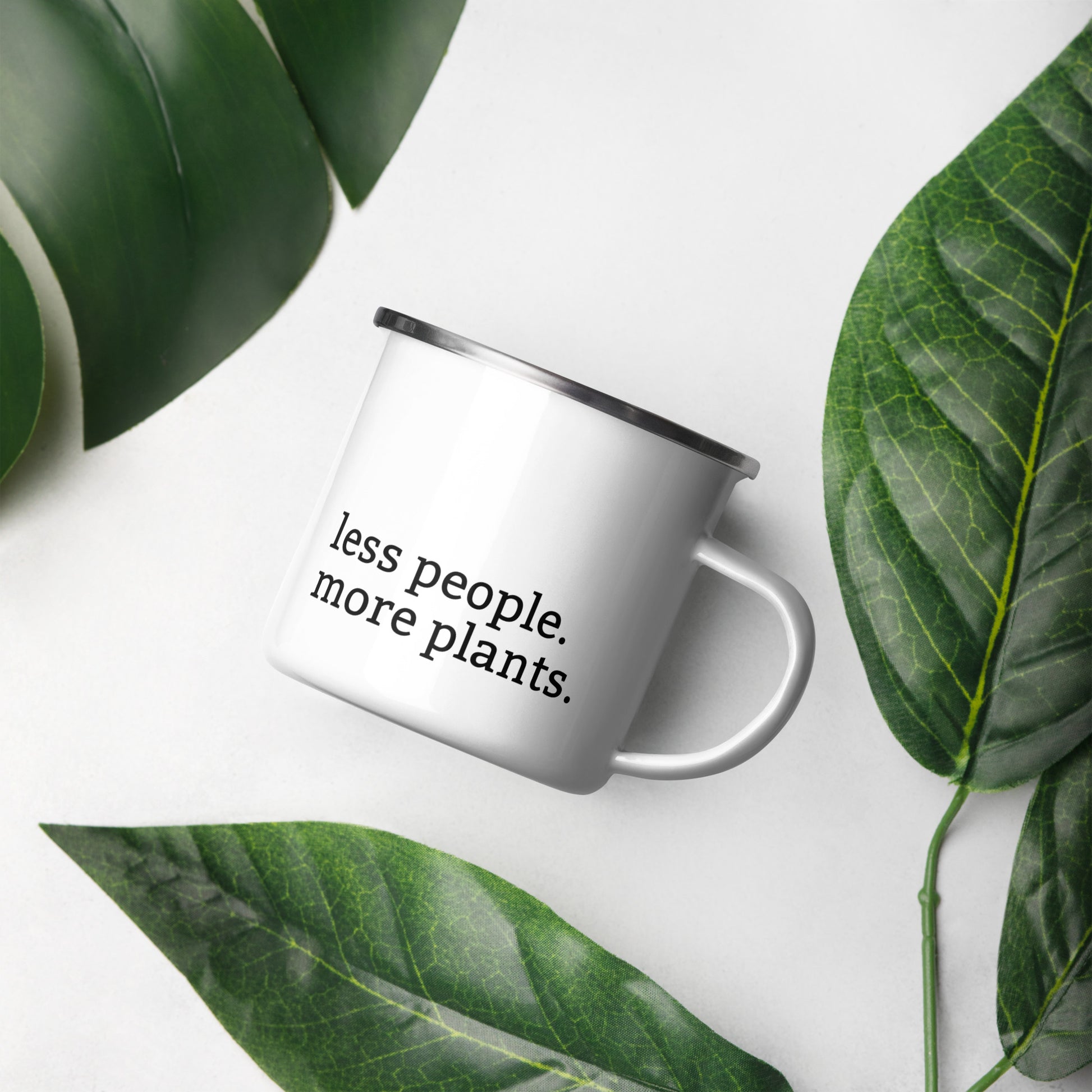 White enamel mug with black rim featuring “Peace in the dirt” and “Less people, more plants” text